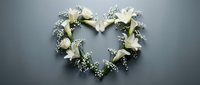 White lily heart wreath with baby's breath on gray background for wedding decoration, sympathy arrangement, romantic floral design and special occasions.