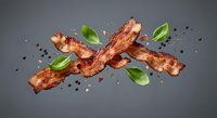 Crispy bacon strips with fresh basil leaves and black pepper on gray background. Perfect for culinary designs, restaurant menus and food advertising projects.