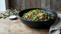 Fresh tabbouleh salad with parsley, tomatoes and bulgur wheat in black bowl on rustic wooden table for healthy Mediterranean cuisine and vegetarian dining.