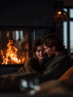 Romantic couple embracing by warm fireplace in cozy living room during intimate evening together at home.
