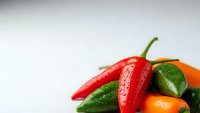Fresh colorful chili peppers mix with water drops on white background, spicy hot vegetables for cooking and culinary recipes preparation.