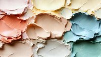 Peeling paint layers in pastel colors creating abstract texture with cracked and chipped surface revealing multiple paint coats underneath.