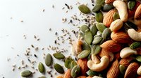 Mixed nuts and seeds scattered on white background with pumpkin seeds, almonds, cashews and chia seeds for healthy snacking and cooking recipes.