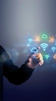 Hand of a person in business attire holding glowing neon wifi, cloud computing, and network icons against blurred urban background for technology and connectivity concepts.