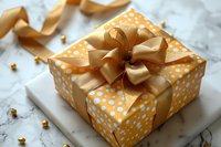 Festive gift box wrapped in orange polka dot paper with elegant golden satin bow on marble surface, perfect for celebration and holiday designs.