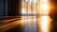 Warm sunlight streaming through window onto polished wooden floor creating dramatic light rays and shadows in elegant interior room with curtains.