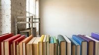 Colorful books arranged in rainbow spectrum on wooden surface in bright modern library interior with natural lighting and minimalist design elements.
