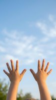 Two hands reaching up toward bright blue sky with white clouds expressing freedom hope and aspiration in warm golden sunlight for wellness concepts.