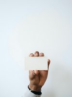 Male hand with medium-deep skin tone holding blank white card against neutral background, suitable for business messaging, corporate branding, advertising campaigns, and promotional materials.