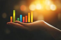 Glowing colorful bar graph floating above an outstretched palm against dark background with golden bokeh lights, representing business growth and data visualization.