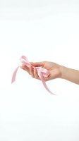 Female hand holding pink ribbon on white background isolated for breast cancer awareness campaign and support cause design.