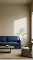 Minimalist living room interior with blue upholstered sofa, wooden coffee table, natural jute rug, and wooden armchair. Sunlight casts tree shadow on beige wall. Modern home decor and interior design.