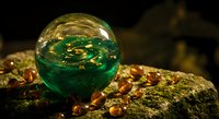Green crystal ball with golden swirls on amber stones creating mystical fortune telling atmosphere for spiritual and esoteric design projects.