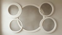 Modern minimalist white circular frames mounted on beige wall creating geometric pattern for contemporary interior design and home decor applications.