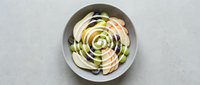 Elegant avocado and radish salad arranged in circular pattern on white plate, fresh healthy vegetarian meal with artistic presentation for culinary content.