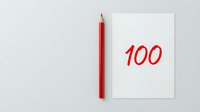 Red pencil beside white paper showing 100 score for academic achievement and educational success concepts.