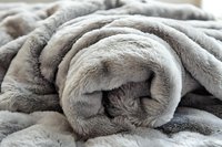 Soft plush gray blanket rolled up showing luxurious texture and cozy folds, perfect for home decor and comfort in winter months.