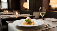 Elegant fine dining restaurant table setting with gourmet dish and white wine glass in upscale atmosphere for culinary hospitality marketing.