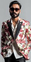 South Asian male model wearing floral print blazer with black lapels, white shirt, and designer sunglasses against gray background. Fashion portrait showcasing luxury menswear.