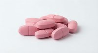 Pink pharmaceutical tablets and capsules scattered on white background for medical healthcare design projects.