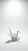 White origami paper crane casting shadow on clean background for minimalist design projects and peaceful meditation concepts.