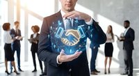 Professional businessman in suit presenting digital handshake hologram with network connections in modern office environment with colleagues in background.