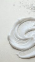 White cream swirl texture on beige background for skincare cosmetics and beauty product design applications.