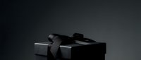 Black gift box with ribbon bow on dark background, suitable for luxury product packaging, holiday promotions, and festive marketing materials.