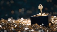 Golden key standing in small black box surrounded by glittering gold jewelry pieces and gems against dark background with bokeh effect.