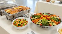 Professional catering setup with chafing dish, colorful vegetable platter and fresh salad bowl for corporate events, weddings and buffet service.