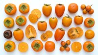Fresh persimmon fruits collection showing whole and sliced orange persimmons with green leaves on white background for healthy eating designs.