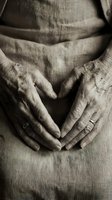 Elderly woman's wrinkled hands forming a heart shape over linen clothing, sepia tone closeup conveying love, aging, and life wisdom.