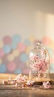 Glass cloche dome with delicate pink cherry blossom branches on rustic wooden surface against soft bokeh background for spring decor and romantic styling.