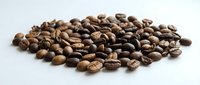 Roasted coffee beans scattered on white background, suitable for beverage packaging, cafe menus, and food industry marketing materials.