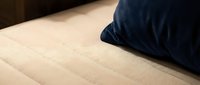 Dark navy pillow resting on beige quilted mattress surface, showcasing bedding texture and comfort for sleep, rest, and bedroom interior design projects.