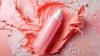 Pink cosmetic bottle with dynamic coral liquid splash and white pearls on pink background. Creative skincare product photography for beauty advertising.