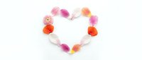 Colorful flower petals arranged in romantic heart shape on white background for Valentine's Day, wedding, love concepts and greeting card designs.