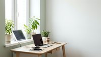 Wooden desk with laptop, solar panel, and potted plants by bright window in minimalist home office workspace for remote work and sustainable living.