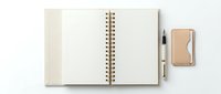 Open spiral notebook with blank pages and matching tan cardboard cover, displayed with coordinating pen and small notebook on white background for stationery and office supplies concepts.