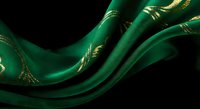 Luxurious emerald green silk fabric with golden ornate patterns flowing elegantly against dark background for premium textile and fashion design projects.