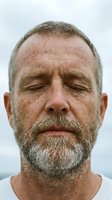 Middle-aged Caucasian man with full gray beard and receding hairline, eyes closed in peaceful expression, isolated portrait against white background for design use.
