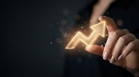 Business professional touching glowing upward arrow chart showing growth and success with sparkling light effects on dark background.