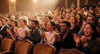 Diverse audience applauding enthusiastically in elegant theater venue during live performance. Mixed age group enjoying entertainment event together.