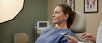 Middle-aged Caucasian woman patient relaxing in modern dental chair during routine checkup appointment at professional clinic office.
