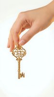 Female hand holding ornate golden vintage key with decorative baroque design isolated on white background for luxury and security concepts.