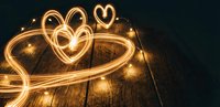 Golden light trails forming heart shapes on wooden floor with sparkling bokeh effects for romantic Valentine's Day celebrations and love concepts.