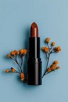 Brown lipstick with dried orange flowers on light blue background, minimal cosmetic composition for beauty and makeup advertising or social media content.