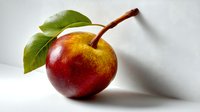 Fresh red and yellow apple with stem and green leaves on white background, isolated for food photography and healthy eating concepts.