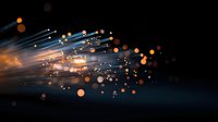 Glowing optical fibers with orange bokeh lights against dark background create dynamic motion effect for technology and communication designs.