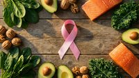 Pink ribbon surrounded by fresh salmon, avocado, nuts, and leafy greens on wooden surface. Represents health awareness and nutritious eating for wellness campaigns.